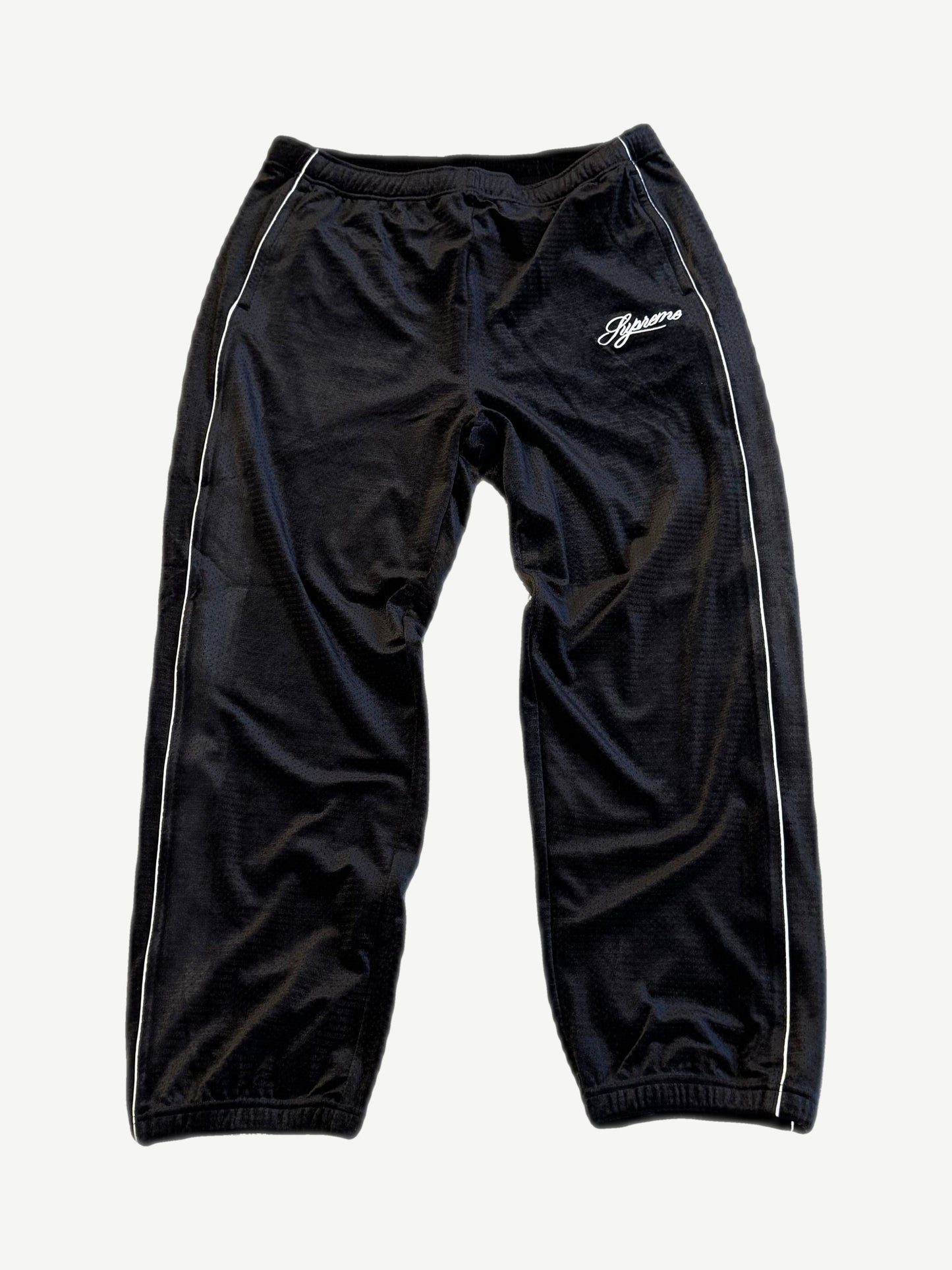 Supreme black velour mesh track pants with white piping side stripes and script Supreme thigh logo.