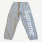 Supreme heather gray sweatpants with large white satin applique Supreme logo running down the right leg