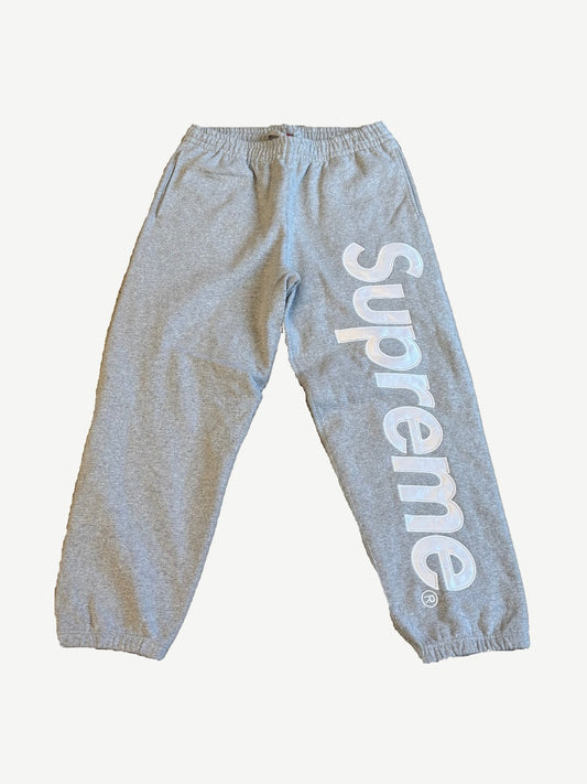 Supreme heather gray sweatpants with large white satin applique Supreme logo running down the right leg