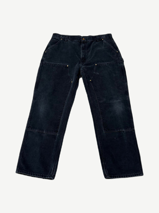 Vintage Carhartt faded black double knee carpenter pants with brass rivets and utility pockets, front view