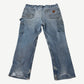 Vintage Carhartt faded blue carpenter pants back view with utility pockets and worn rugged fabric.