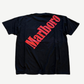 Vintage Marlboro big logo tee back, large red diagonal Marlboro wordmark print across black cotton body.