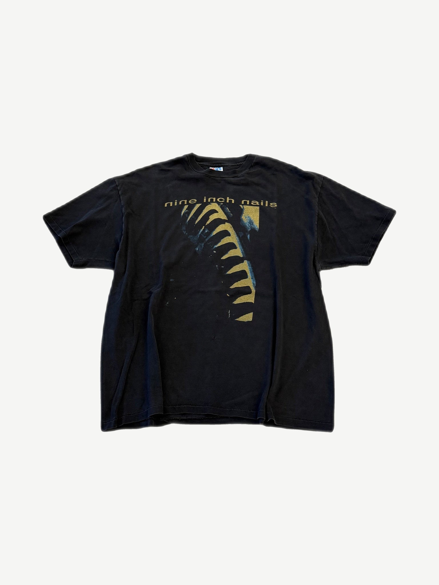 Vintage Nine Inch Nails Now I'm Nothing tee in black with gold ribcage graphic and band logo on chest.