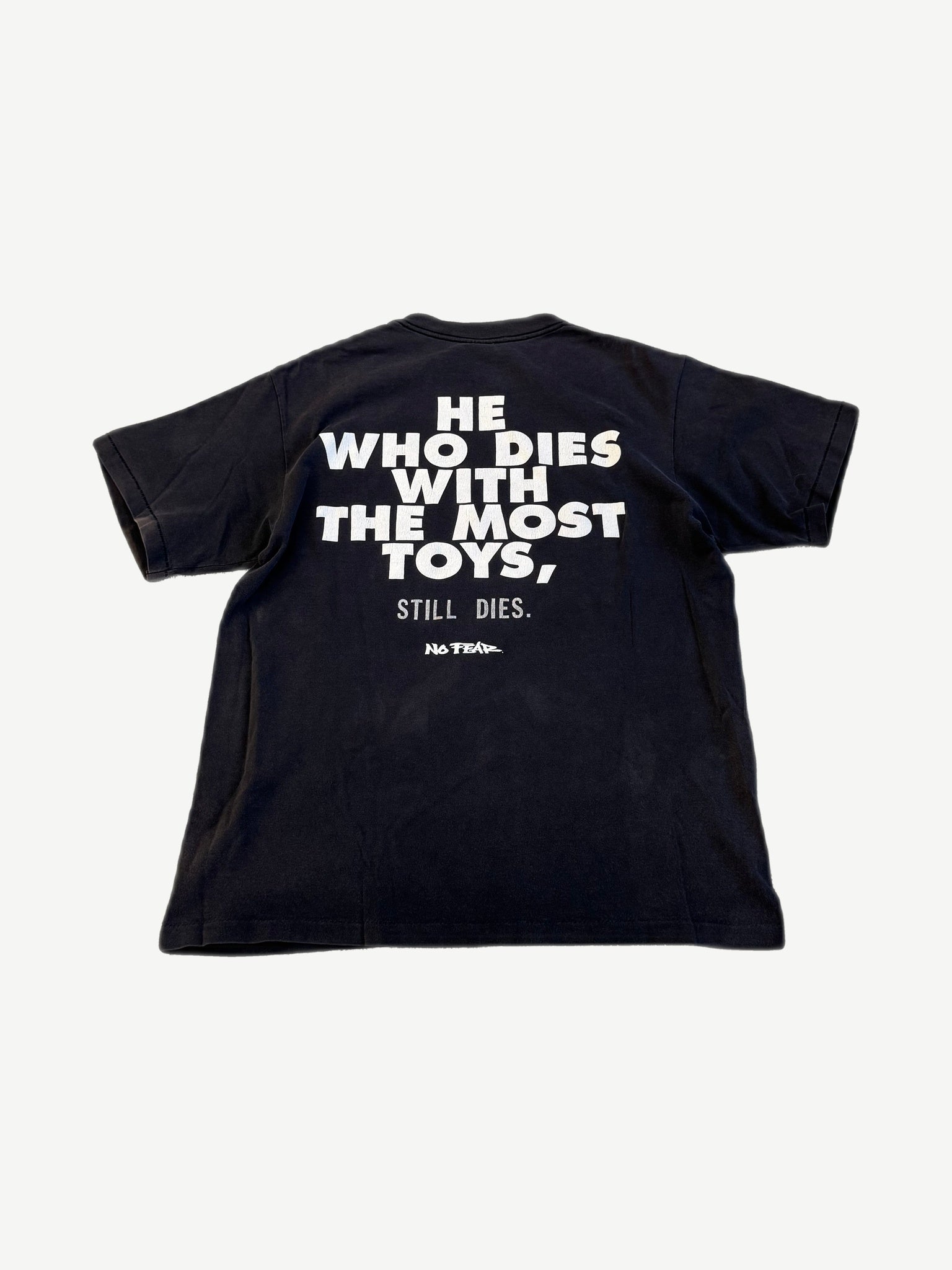 Vintage No Fear black tee back with bold He Who Dies With The Most Toys Still Dies slogan print