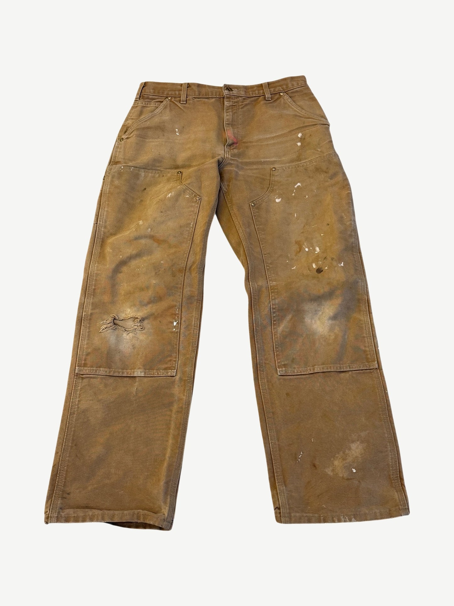 Vintage tan Carhartt double knee carpenter pants front view, heavily worn canvas with paint splatter and knee blowout.